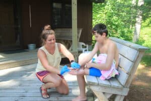 nurse helping a camper with a wound on their toe.