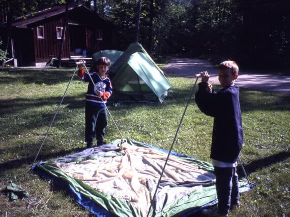 Two young campers learning to setup a tent in preparation for a canoe trip.