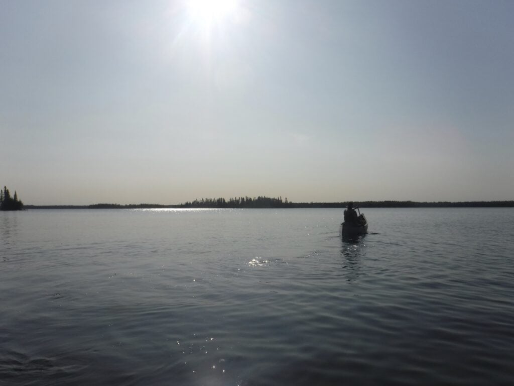 Paddling a Camp Chippewa canoe during a beautiful summer day on a lake in Canada.