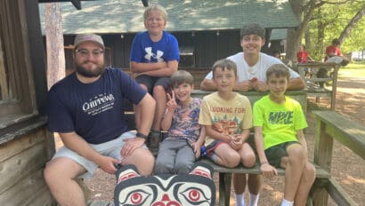 Four campers sit with two counselors on a deck at Camp Chippewa for Boys in Minnesota.