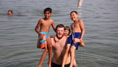 a counselor holding three campers while playing in the lake.