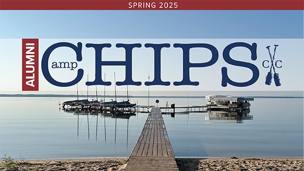 Alumni Camp Chips Spring 2025 Issue cover image of the Cass Lake waterfront showing a dock leading out from a sandy beach to sailboats and other watercraft on a calm lake
