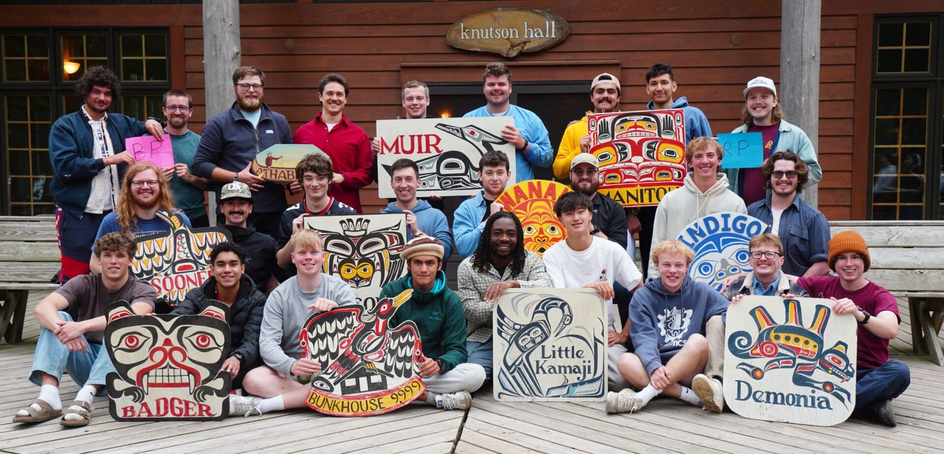 group of summer camp counselors holding cabin signs.