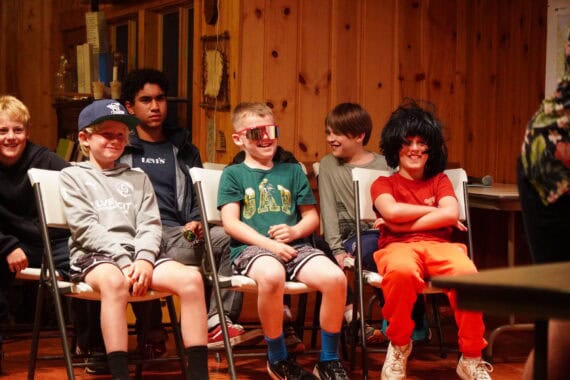 three boys sitting in chairs dressed up in costumes.