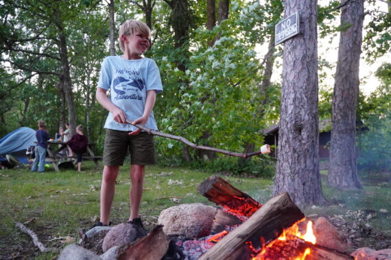 boy roasting smores and smiling by campfire.