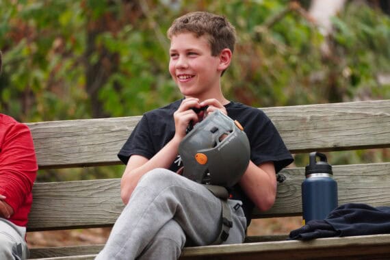 boy with climbing helmet sitting on bench and smiling.