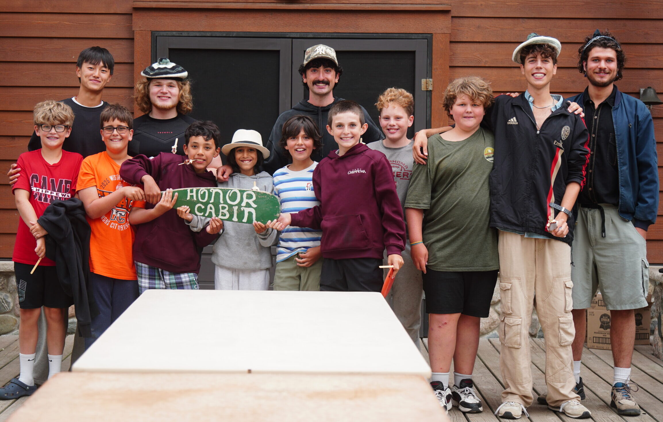 group of campers and counselors holding up honor cabin sign and smiling.