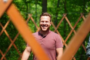 maintenance man smiling inside yurt frame.