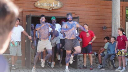 two men painted in blue dancing on deck.